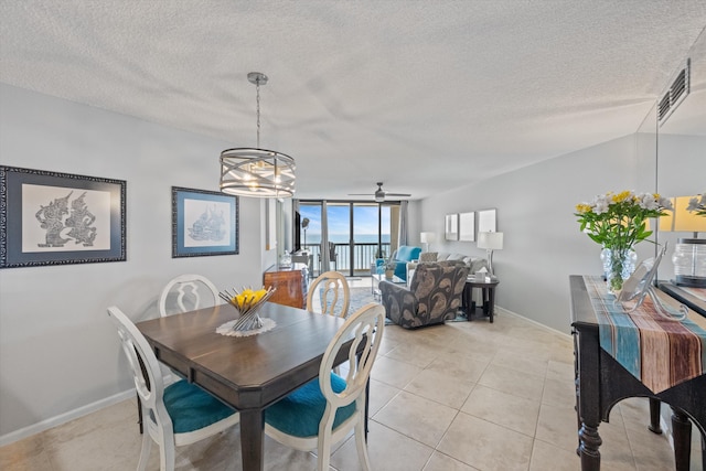 tiled dining room featuring ceiling fan with notable chandelier and a textured ceiling