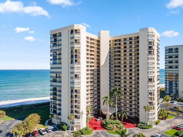 view of property with a water view and a beach view