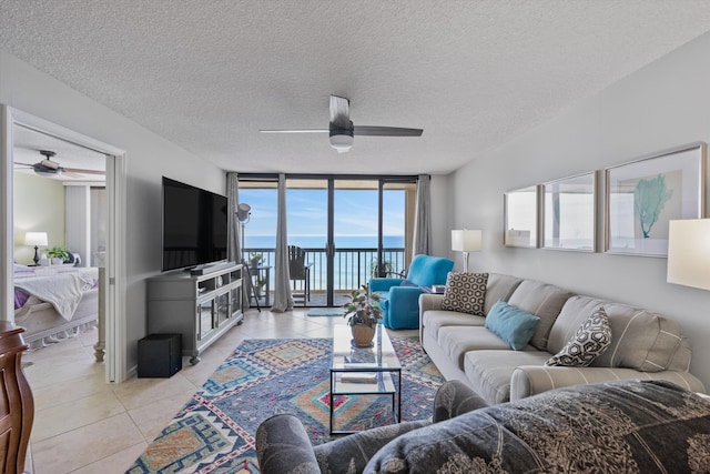 living room featuring floor to ceiling windows, ceiling fan, light tile patterned floors, and a textured ceiling