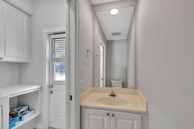 bathroom with decorative backsplash, vanity, and toilet