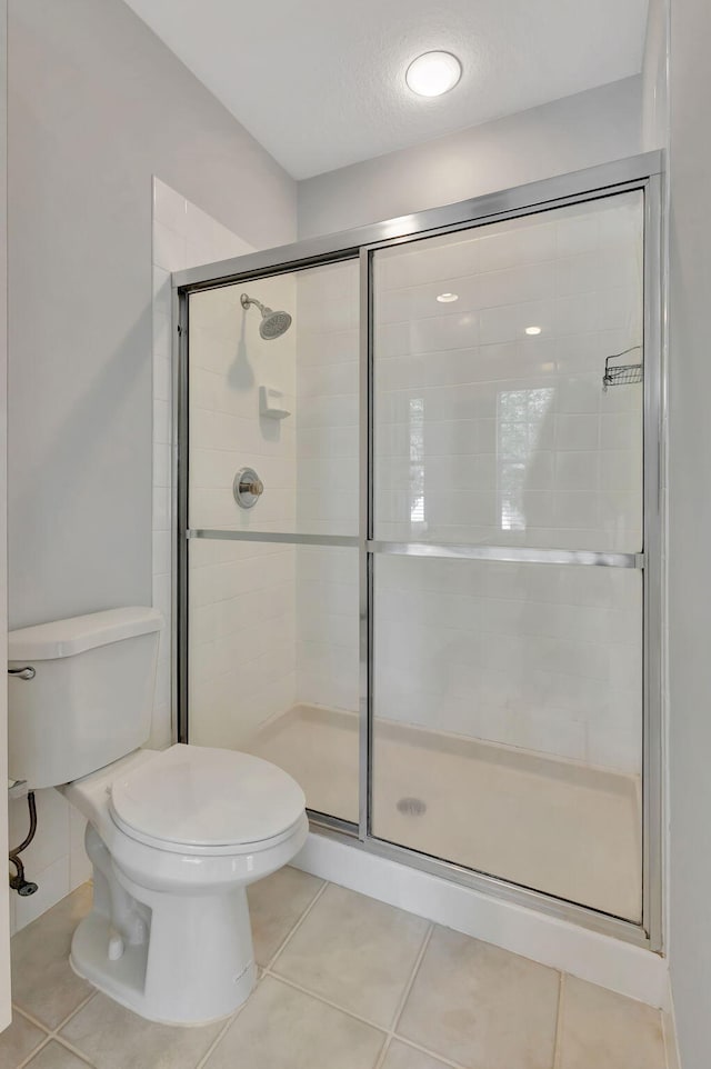 bathroom with tile patterned floors, a shower with door, a textured ceiling, and toilet