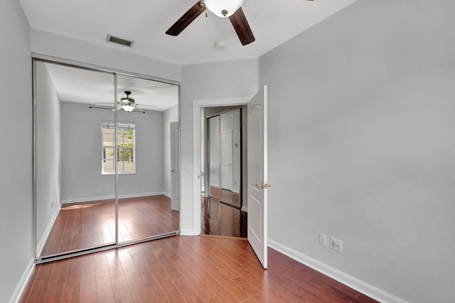 unfurnished bedroom with ceiling fan, a closet, and wood-type flooring