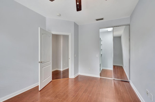 unfurnished bedroom with a closet, hardwood / wood-style flooring, and ceiling fan