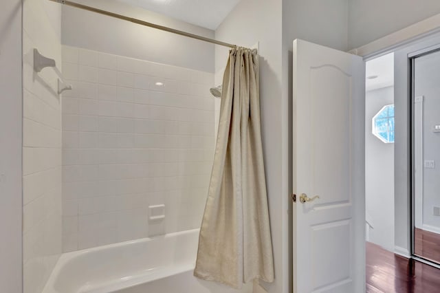 bathroom with hardwood / wood-style flooring and shower / tub combo with curtain