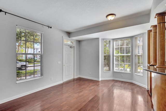 empty room with a wealth of natural light and hardwood / wood-style flooring