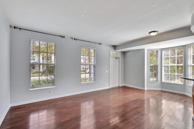 empty room with dark hardwood / wood-style flooring and a textured ceiling