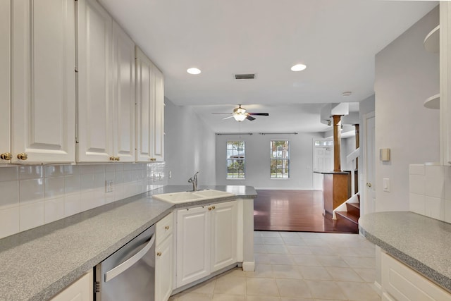 kitchen with stainless steel dishwasher, white cabinets, light wood-type flooring, and tasteful backsplash