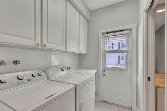 laundry area with washing machine and clothes dryer, light tile patterned flooring, and cabinets