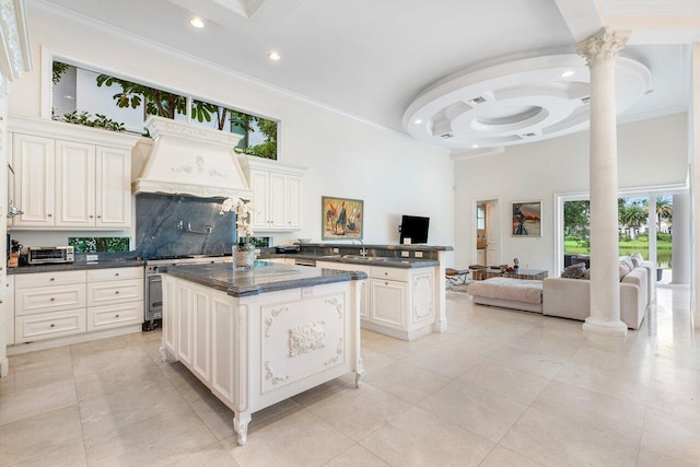 kitchen featuring sink, a center island, a high ceiling, tasteful backsplash, and ornamental molding