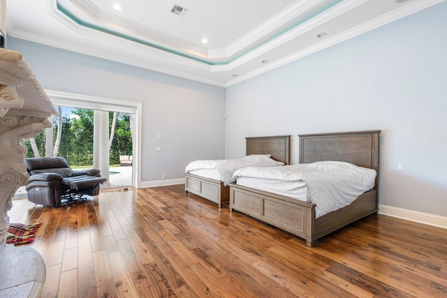 bedroom featuring hardwood / wood-style flooring, a raised ceiling, access to exterior, and crown molding