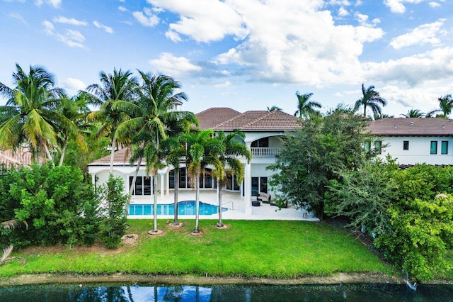 back of property featuring a patio, a balcony, a lawn, and a water view