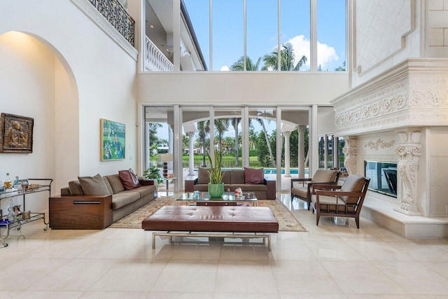 living room with a healthy amount of sunlight, a towering ceiling, a fireplace, and light tile patterned floors