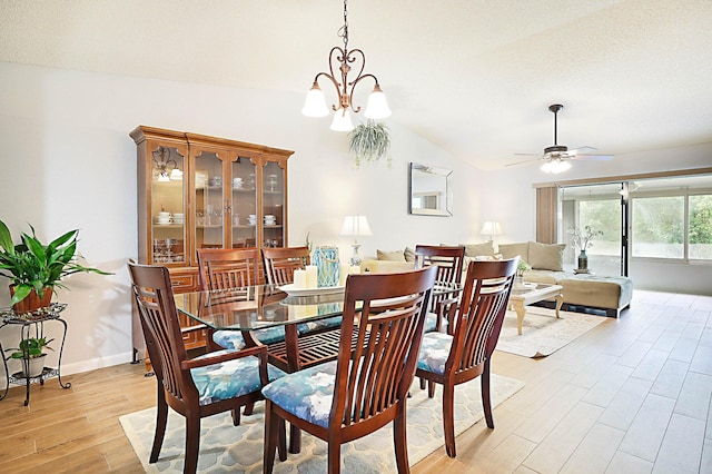 dining room featuring ceiling fan with notable chandelier, light hardwood / wood-style floors, and vaulted ceiling