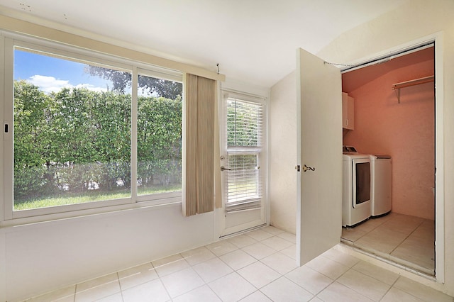 laundry area with washing machine and clothes dryer, a wealth of natural light, light tile patterned flooring, and cabinets