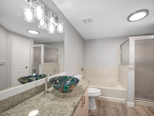 full bathroom with vanity, hardwood / wood-style flooring, separate shower and tub, toilet, and a textured ceiling