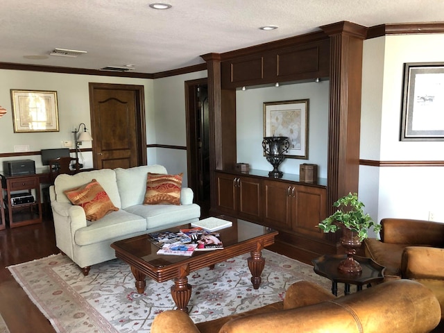 living room featuring hardwood / wood-style flooring, ornamental molding, and a textured ceiling