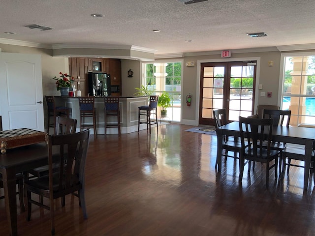 dining room with french doors, dark hardwood / wood-style flooring, a textured ceiling, and crown molding