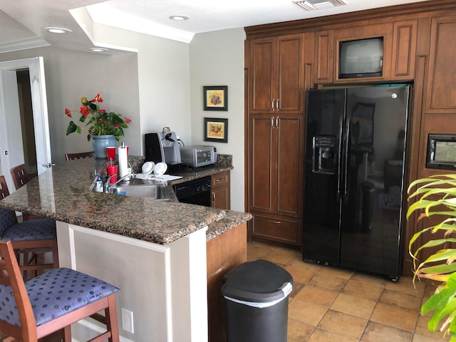 kitchen featuring dark stone counters, a breakfast bar, sink, black appliances, and light tile patterned flooring