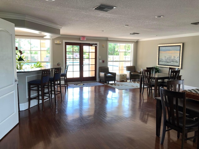 dining area with a textured ceiling, dark hardwood / wood-style flooring, french doors, and ornamental molding