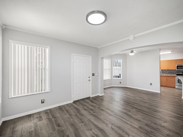 unfurnished living room with ceiling fan, crown molding, and dark wood-type flooring