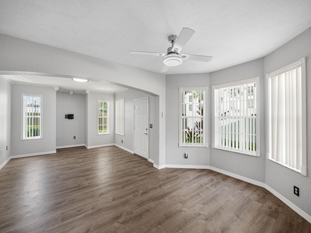 spare room featuring a textured ceiling, ceiling fan, dark wood-type flooring, and a wealth of natural light