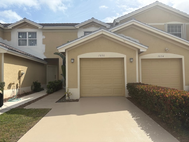 multi unit property with concrete driveway, a garage, and stucco siding