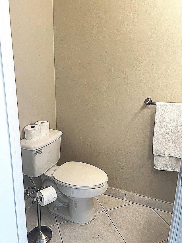 bathroom with baseboards, toilet, and tile patterned flooring