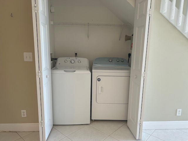 laundry room with laundry area, light tile patterned floors, washing machine and dryer, and baseboards