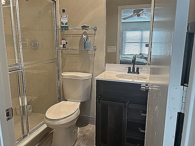 bathroom with vanity, wood finished floors, baseboards, a stall shower, and toilet