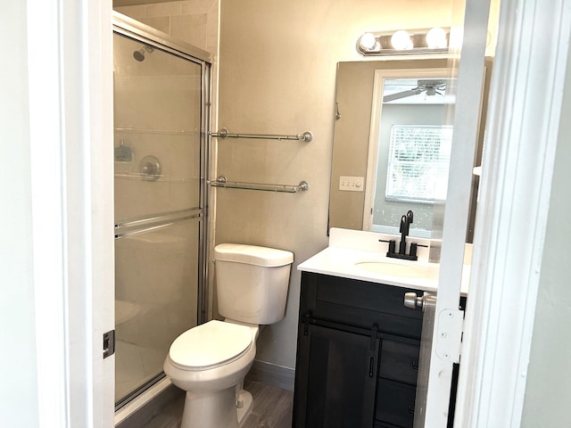 bathroom with baseboards, toilet, a stall shower, wood finished floors, and vanity