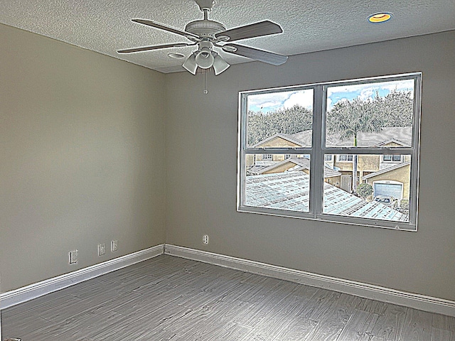 spare room featuring ceiling fan, a textured ceiling, baseboards, and wood finished floors