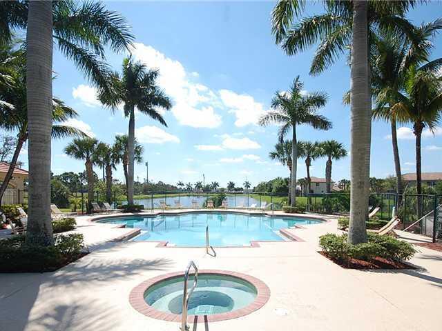 community pool with a patio, fence, and a hot tub