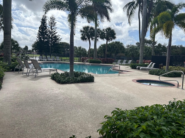 pool with a hot tub, a patio, and fence