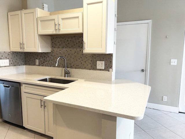 kitchen featuring a sink, backsplash, stainless steel dishwasher, a peninsula, and light tile patterned floors