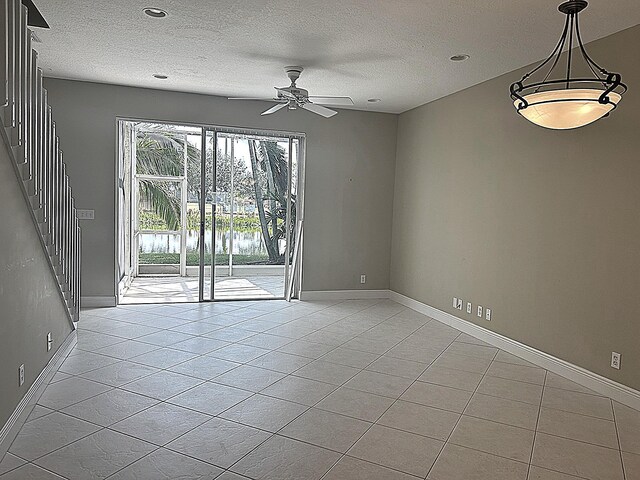 empty room featuring stairway, a textured ceiling, baseboards, and a ceiling fan