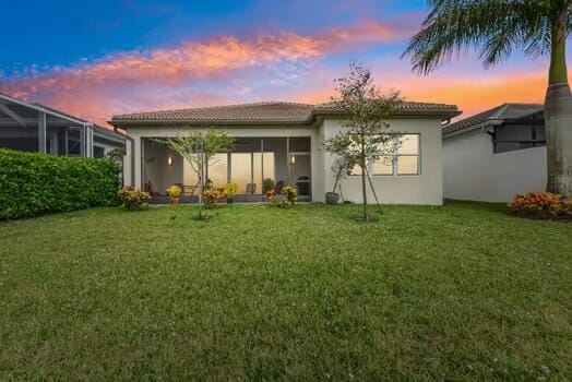 back house at dusk with a lawn