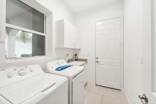 washroom with cabinets, light tile patterned floors, sink, and washing machine and clothes dryer