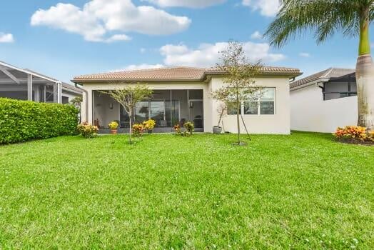 rear view of property with a lawn and a sunroom