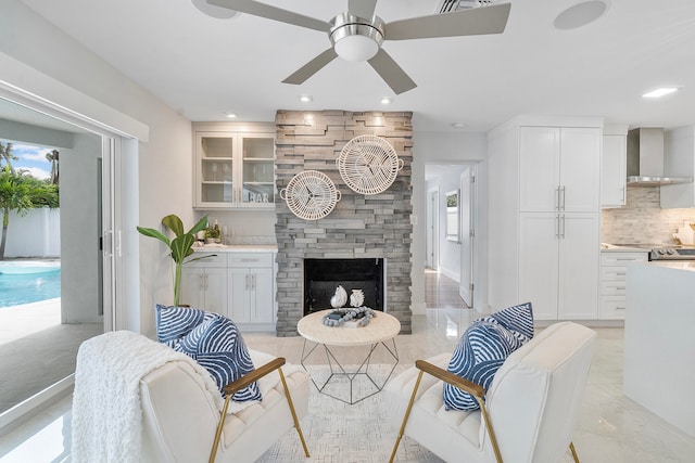 living room with ceiling fan and a fireplace