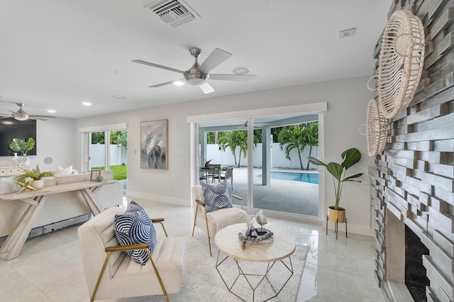 tiled living room with a fireplace, ceiling fan, and plenty of natural light