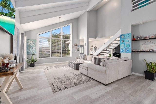 living area with high vaulted ceiling, baseboards, stairway, and wood finished floors