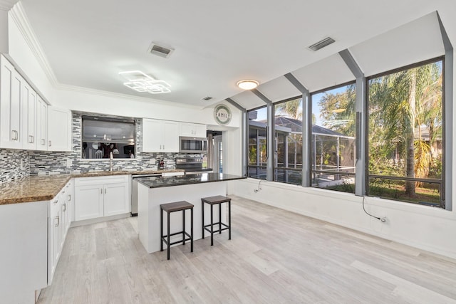 kitchen featuring visible vents, a kitchen island, backsplash, and white cabinetry