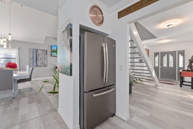 kitchen with crown molding, visible vents, light wood-style flooring, freestanding refrigerator, and baseboards