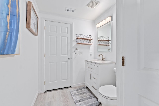 bathroom with visible vents, vanity, toilet, and wood finished floors