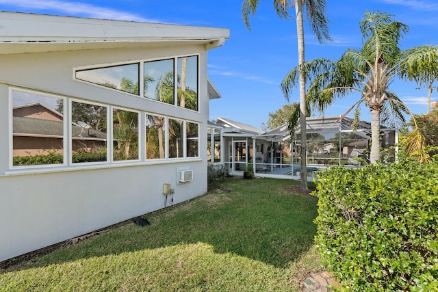 exterior space featuring glass enclosure, a lawn, and stucco siding