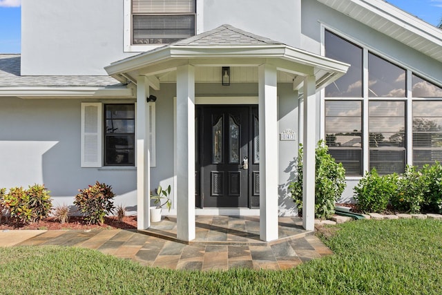 entrance to property featuring a shingled roof and stucco siding