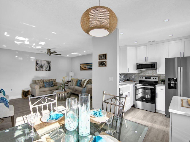 dining area featuring ceiling fan, sink, and light hardwood / wood-style floors