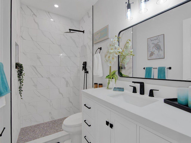 bathroom with vanity, toilet, and a tile shower