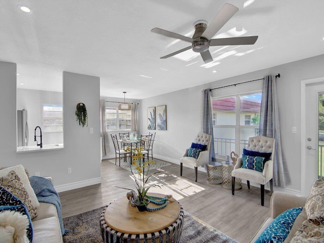 living room featuring hardwood / wood-style flooring, ceiling fan, and sink