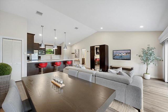 dining space with light hardwood / wood-style flooring and vaulted ceiling